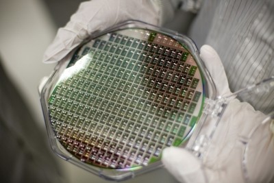 A researcher displays chips that integrate germanium lasers. In 2010, Lionel Kimerling and his colleagues demonstrated the first such lasers that can produce wavelengths of light useful for optical communication and operate at room temperature. Photo: MIT Microphotonics Center